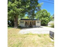 Charming one-story home with a covered front porch and large mature trees on a sunny day at 1307 Washington Ln, Kannapolis, NC 28083