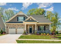 Charming home featuring a stone facade, two-car garage, covered porch, and beautifully landscaped front yard at 19006 Brandon James Dr, Cornelius, NC 28031