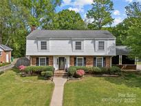 Classic two-story home features a landscaped front yard, brick and shingle facade, and inviting walkway to the front door at 6035 Idlebrook Dr, Charlotte, NC 28212