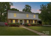 Two-story home boasts a well-maintained front yard, brick facade, complemented by symmetrical shrubbery and a paved walkway at 6035 Idlebrook Dr, Charlotte, NC 28212