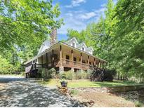 Charming two-story home featuring a spacious porch, stone chimney, and lush landscaping at 729 Lochaven Rd, Waxhaw, NC 28173