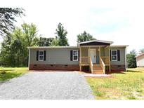 Charming single-story home features a covered porch, gravel driveway and tidy landscaping at 828 Long Bow Rd, Salisbury, NC 28144