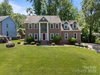 Two-story brick home featuring a red door, landscaped front yard and lush green trees at 9000 Stourbridge Dr, Huntersville, NC 28078