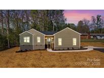 A single-story home showcasing a well-maintained lawn, fresh landscaping, and a charming entryway at 9165 Cherokee Dr, Hickory, NC 28601