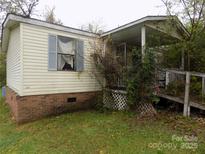 Shows the exterior of a single story home with a covered porch and overgrown landscaping at 107 N Rudisill Ave, Cherryville, NC 28021