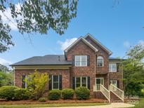 Beautiful two story brick home with manicured front yard and stairs to the front door at 1121 Setter Se Ln, Concord, NC 28025