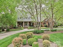 Charming brick home with a covered porch, manicured landscaping, and a circular driveway at 1126 Concord Rd, Davidson, NC 28036