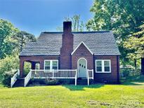 Charming brick home featuring a classic white-trimmed porch and a well-maintained front lawn at 121 W 11Th St, Oakboro, NC 28129