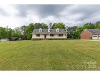 Inviting yellow house with a charming front porch and a large, well-maintained front yard at 1990 Country Club Dr, Lancaster, SC 29720