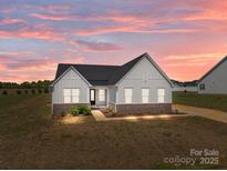 Charming exterior of a single-story home with white siding, black roof, and manicured front yard at sunset at 210 Goldenrod Cir, Salisbury, NC 28147