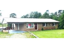 Charming single-story brick home with a metal roof and attached carport surrounded by a green lawn at 7527 Old Shelby Rd, Vale, NC 28168