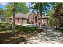 Charming brick home with lush landscaping, mature trees, and a spacious driveway leading to an attached garage at 7748 Long Bay Pkwy, Catawba, NC 28609