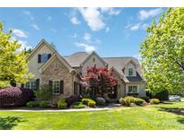 Stunning stone and stucco home with a lush, landscaped front yard on a sunny day at 9200 Kingsmead Ln, Waxhaw, NC 28173