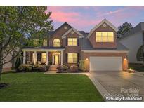Charming brick home featuring a well-manicured lawn, covered porch, and two-car garage, captured at twilight at 9715 Aragorn Nw Ln, Charlotte, NC 28269