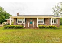 Charming brick home with covered front porch and inviting teal door with colorful wreath at 1162 E Doc Garris Rd, Lancaster, SC 29720