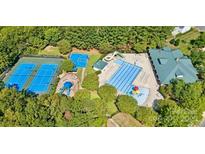 Aerial view of the community pool, tennis courts, playground and clubhouse with lush green surroundings at 14220 Stewarts Bend Ln, Charlotte, NC 28277