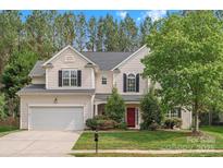 Charming two-story home with a well-manicured lawn, red door, and attached two car garage at 14220 Stewarts Bend Ln, Charlotte, NC 28277