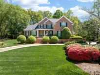 Charming brick two-story home with manicured lawn and lush landscaping under a sunny, partly cloudy sky at 17040 Jetton Rd, Cornelius, NC 28031