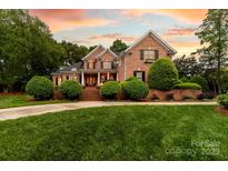 Charming brick two-story home with manicured lawn and lush landscaping under a colorful sunset sky at 17040 Jetton Rd, Cornelius, NC 28031