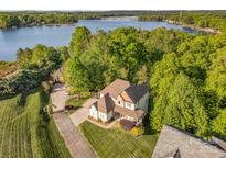 Stunning aerial view showcases the home's proximity to the lake, surrounded by lush greenery and a meticulously maintained lawn at 1713 Mt Isle Harbor Dr, Charlotte, NC 28214