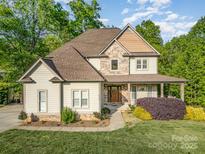 Charming two-story home features a stone and siding exterior, complemented by a covered front porch and landscaped yard at 1713 Mt Isle Harbor Dr, Charlotte, NC 28214