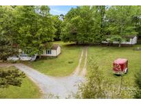 A sprawling property with multiple homes, mature trees, a gravel driveway, and a red horse trailer at 124 Neumann Run, Belmont, NC 28012