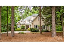Traditional home with tan siding and stone accents nestled among lush trees and landscaping at 19729 Callaway Hills Ln, Davidson, NC 28036