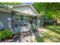 Charming gray-brick home featuring a cozy front porch with decorative metal railings and outdoor seating at 2601 Dora Dr, Charlotte, NC 28215