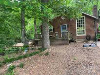 Charming brown home with a blue door, large window, and wooden deck nestled among mature trees at 33611 Mann Rd, Albemarle, NC 28001