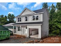 Two-story home featuring gray siding, black roof, open garage, and charming curb appeal against a blue sky backdrop at 530 Gantt St, Mooresville, NC 28115