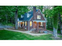 Charming brick home featuring manicured lawn, covered porch, and mature trees, perfect for serene living at 625 4Th Street Nw Dr, Hickory, NC 28601
