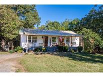 Charming cottage-style home with a welcoming front porch, lush landscaping, and a metal roof at 6312 Bill Ledford Rd, Vale, NC 28168