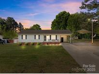 Charming single-story home featuring manicured lawn, carport, and inviting front porch with cozy bench seating at 1238 Moss Springs Rd, Albemarle, NC 28001