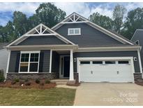 Charming craftsman-style home featuring a two-car garage, stone accents, and eye-catching gable details at 142 Prestwick Way # 18, Mooresville, NC 28115