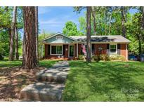 Charming brick home with a well-manicured lawn and inviting walkway, nestled among mature trees at 1501 Briarfield Dr, Charlotte, NC 28205