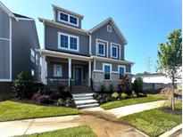 Charming gray two-story home with white trim, manicured lawn and inviting front porch and tasteful landscaping at 19044 Newburg Hill Rd, Davidson, NC 28036