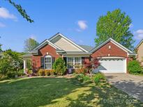 Charming brick home with a well-manicured lawn and landscaping, complemented by a two-car garage at 281 Loch Stone St, Fort Mill, SC 29715