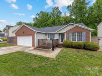 Charming single-story home with brick accents, a wooden deck, an attached two-car garage, and a well-maintained lawn at 3022 Willamette Valley Dr, Charlotte, NC 28215