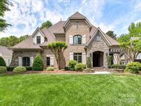 Elegant brick and stone home showcasing a meticulously landscaped lawn and charming architectural details at 825 Hudson Pl, Davidson, NC 28036