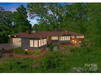 Stunning elevated home with a brick facade, modern gray siding, and large windows surrounded by lush greenery at 916 E Park Dr, Lincolnton, NC 28092