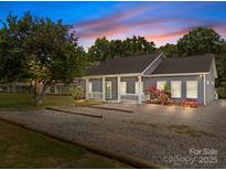 Charming home featuring a gravel driveway, covered front porch, fresh landscaping, and inviting curb appeal at 14532 E Rocky River Rd, Davidson, NC 28036