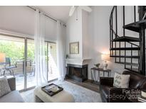 Bright living room featuring a fireplace, spiral staircase, and sliding glass doors to the deck at 2504 Stradbrook Dr # B, Charlotte, NC 28210