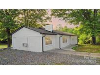 Charming white brick ranch home with a black roof and a large gravel driveway at 5520 Chestnut Dr, Hickory, NC 28602