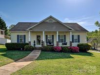 Charming single-story home featuring a covered front porch with swing, lush landscaping, and a well-manicured lawn at 1009 Preston Dr, Lowell, NC 28098
