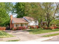 Charming home with a brick chimney, colorful flower beds, and a spacious front yard surrounded by mature trees at 1114 Hartford Ave, Charlotte, NC 28209
