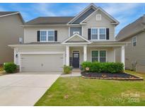 Charming two-story home with a well-manicured lawn, welcoming front porch, and an attached two-car garage at 2014 Burton Point Ct, Waxhaw, NC 28173