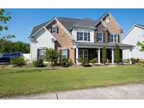 Charming two-story home with a mix of stone and wood siding, lush lawn, and inviting front porch at 2380 Fairport Se Dr, Concord, NC 28025