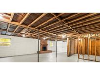 Unfinished basement featuring exposed ceiling beams and a brick fireplace, offering potential for customization at 4110 Charles Raper Jonas Hwy, Alexis, NC 28006