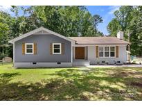 Charming home featuring a mix of gray siding and white brick with wood shutters, complemented by a well-maintained lawn at 7141 Pitchfork Ln, Mint Hill, NC 28227