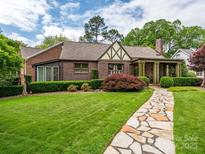 Charming brick home with a stone walkway, manicured lawn, and lush landscaping at 1596 Clayton Dr, Charlotte, NC 28203